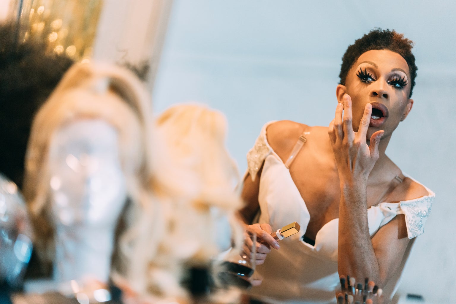 Drag queen getting ready applying lipstick in mirror