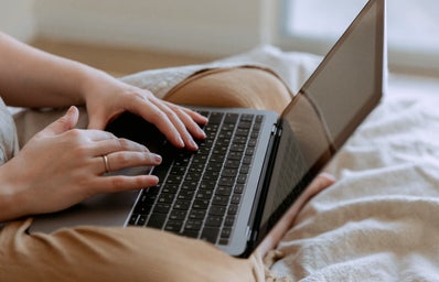 A woman with a ring types on a laptop.