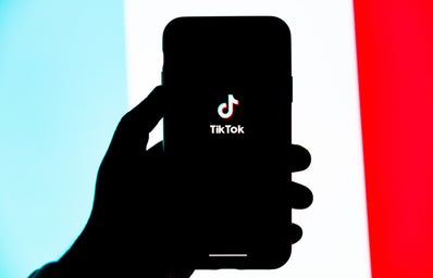 a person\'s hand holding a phone with the tiktok screen open