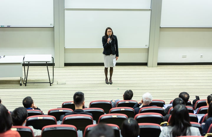 Woman speaking with a microphone in front of a class