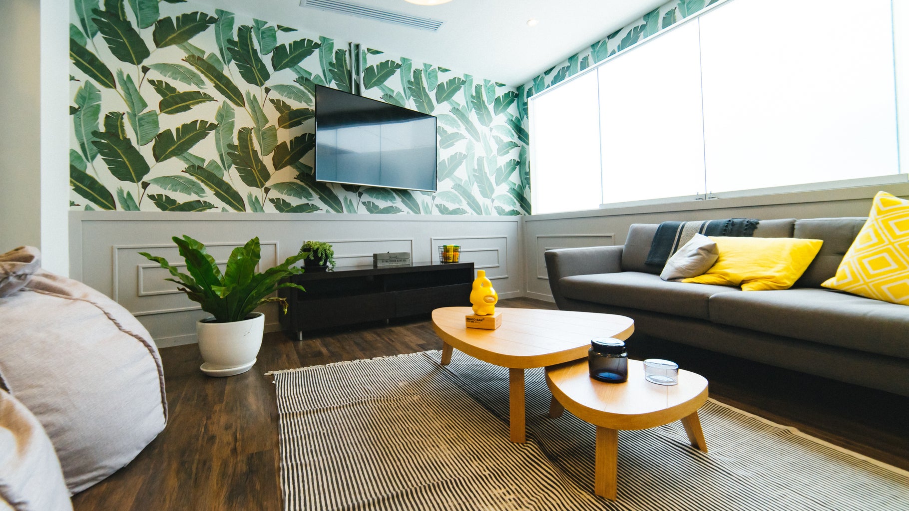 living room with gray couch and plant wallpaper