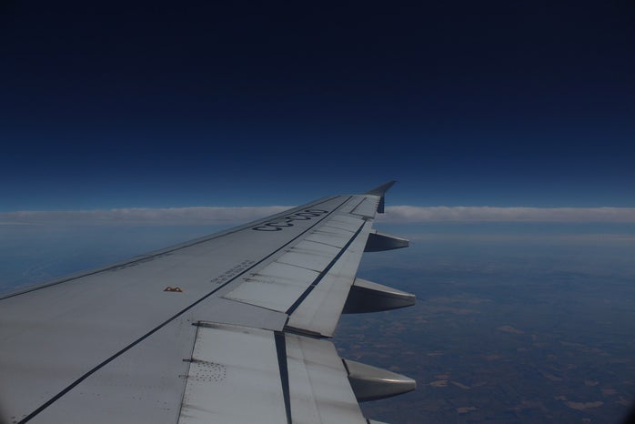 Picture outside of airplane window showing the sky and wing of the plane.