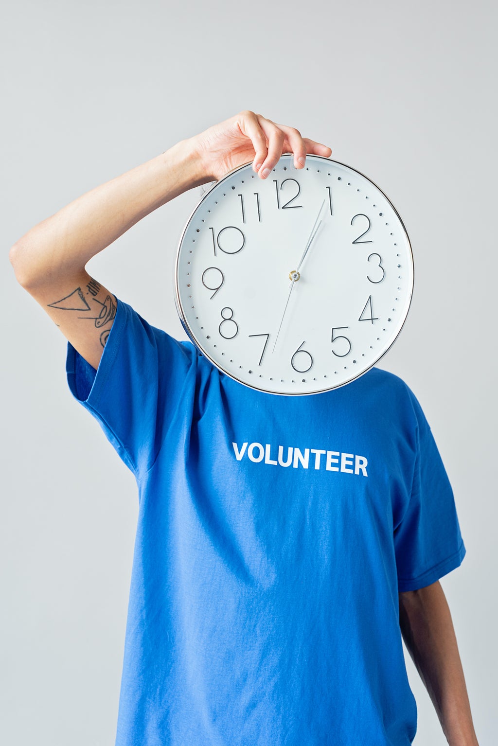 A Person in Blue Shirt Covering It\'s Face Using a Clock