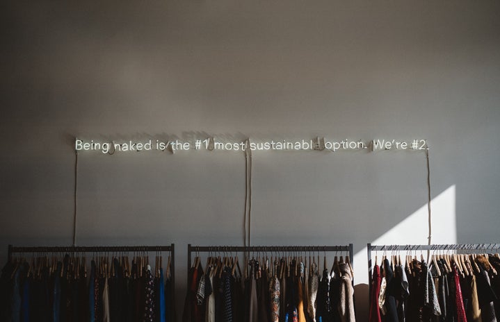 racks of clothing against a wall with a slogan written above them