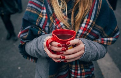 Girl with red manicure holding a red mug. She is wearing a plaid scarf. Fall vibes, cozy.