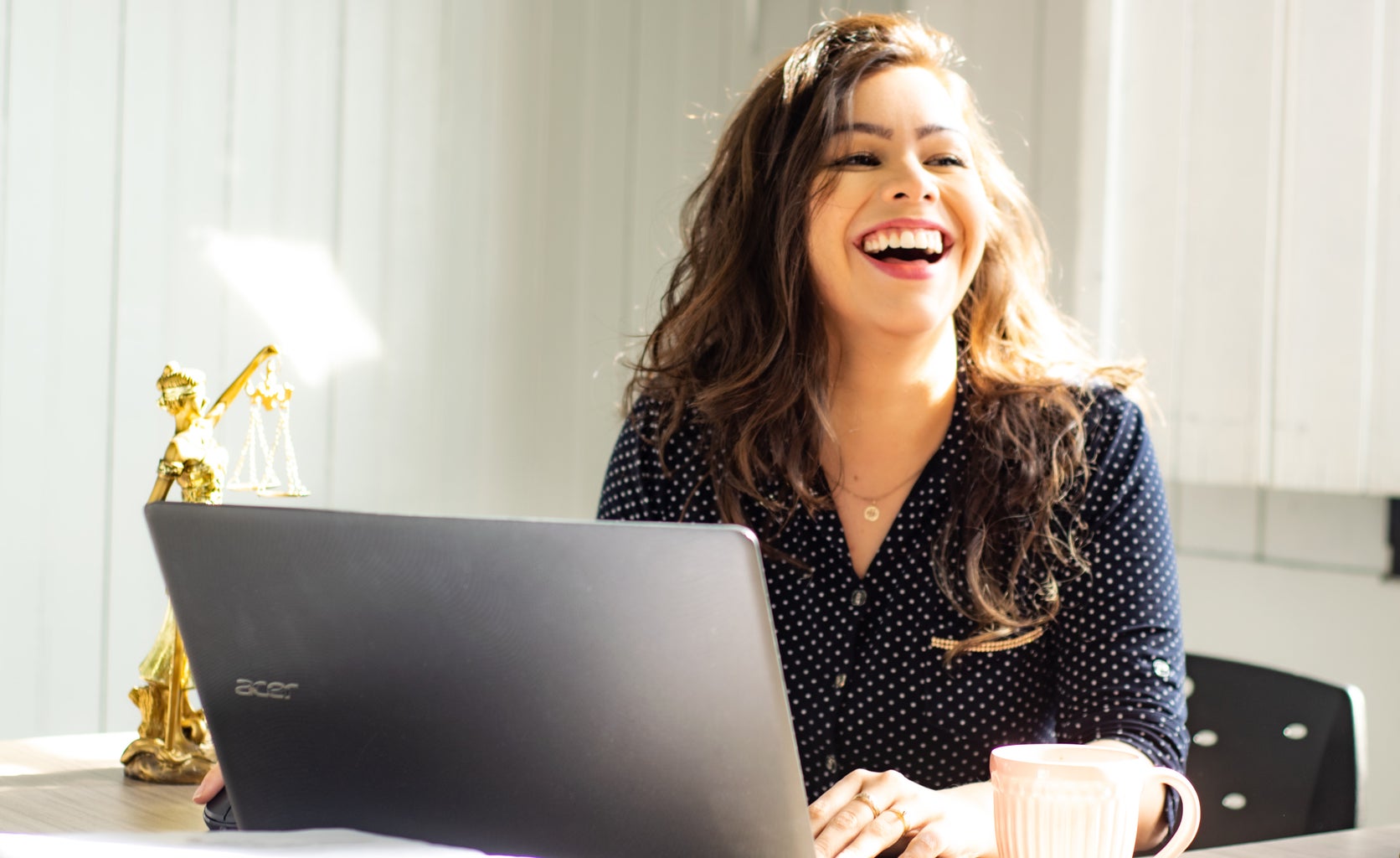 Woman laughs while working on computer.