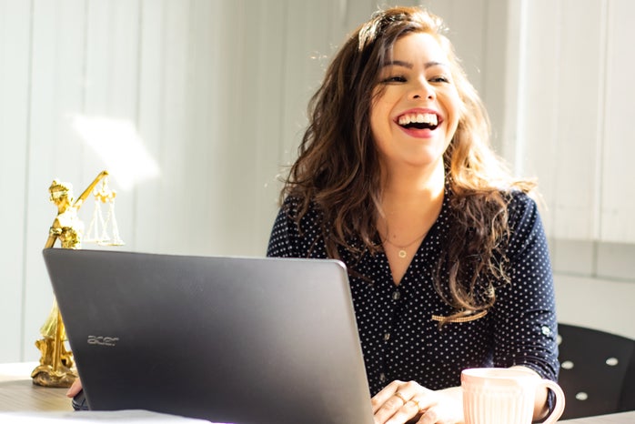 Woman laughs while working on computer.