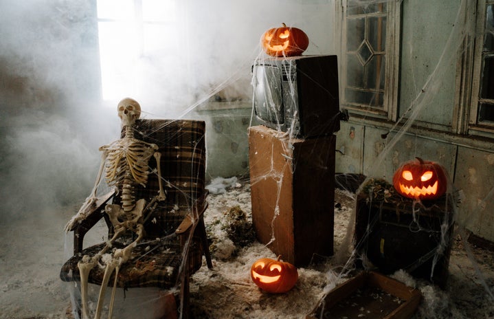 a skeleton in a chair, jack-o-lanterns, and cobwebs.
