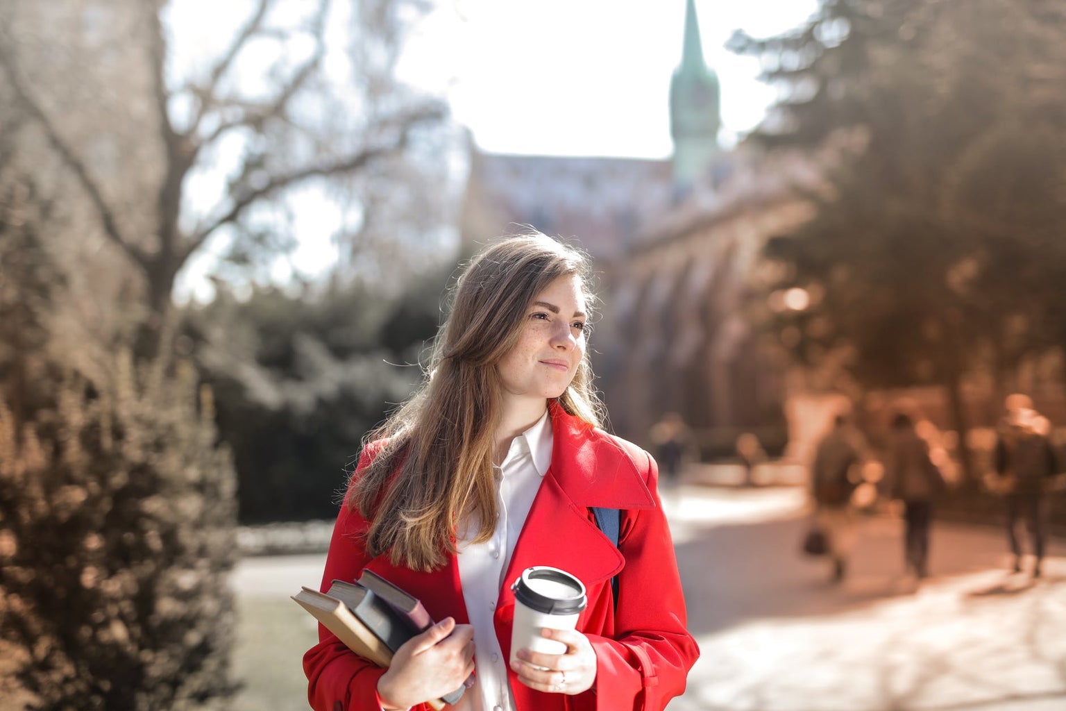 woman holding textbooks and coffee