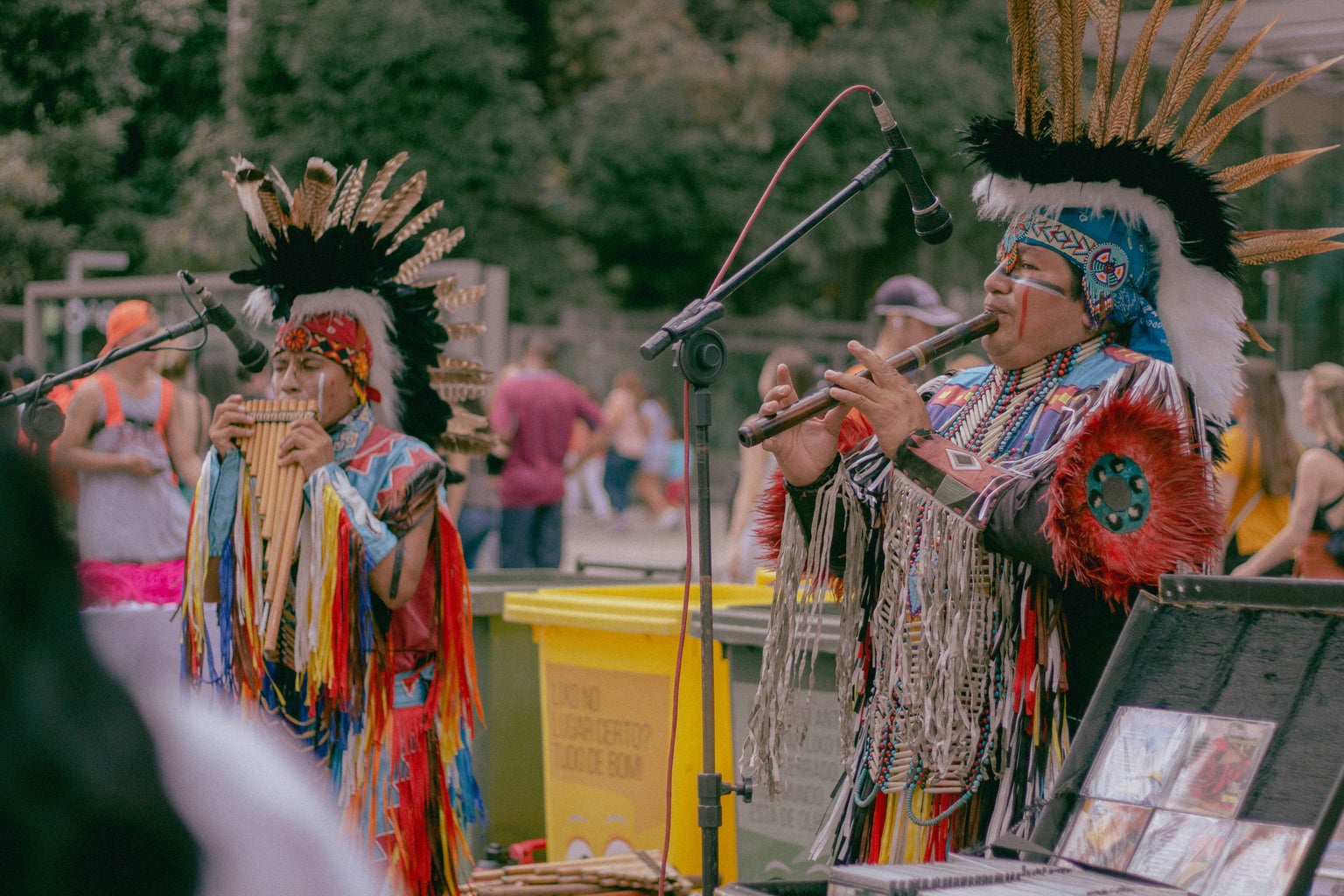 two native americans playing woodwind instruments in traditional clothing