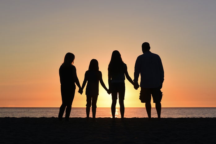 four people holding hands on the beach