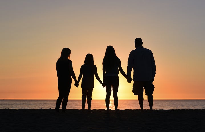 four people holding hands on the beach