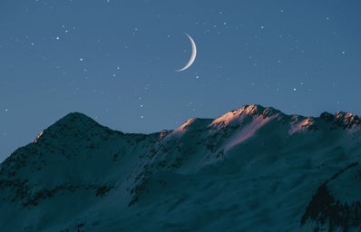 crescent moon above mountains