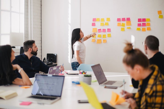 Woman placing sticky notes on wall in office meeting
