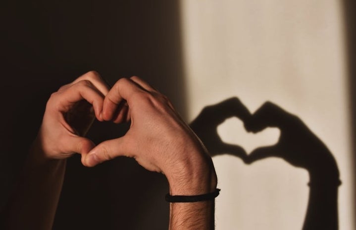 Person doing the shape of a heart, and there is a shadow behind it