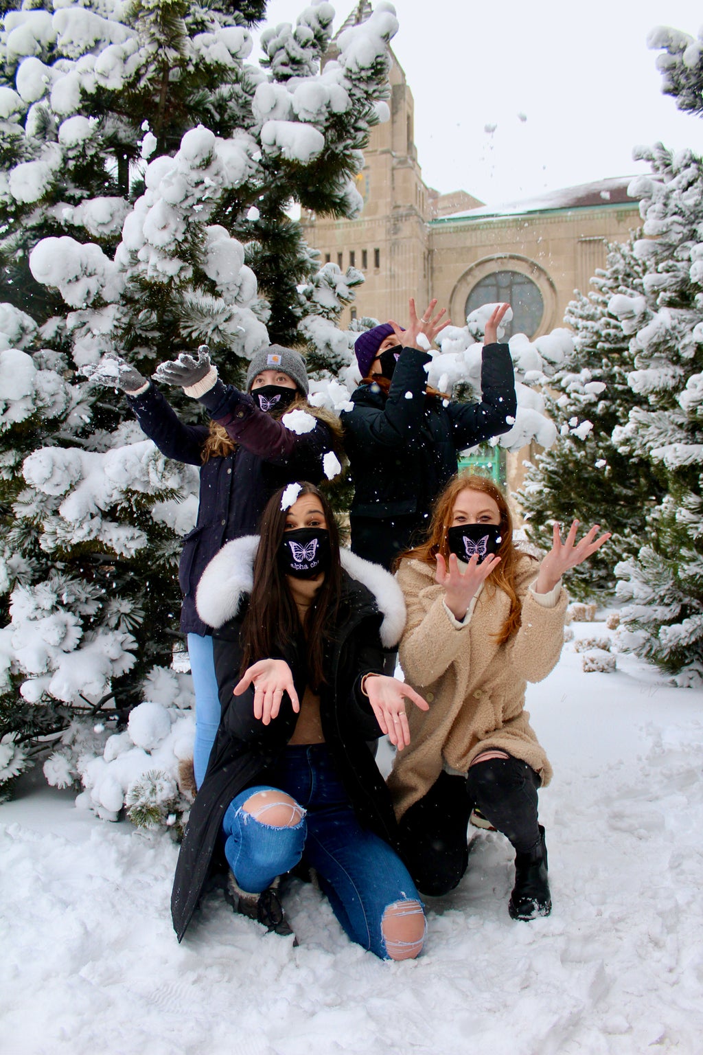 Four women throwing snow on campus