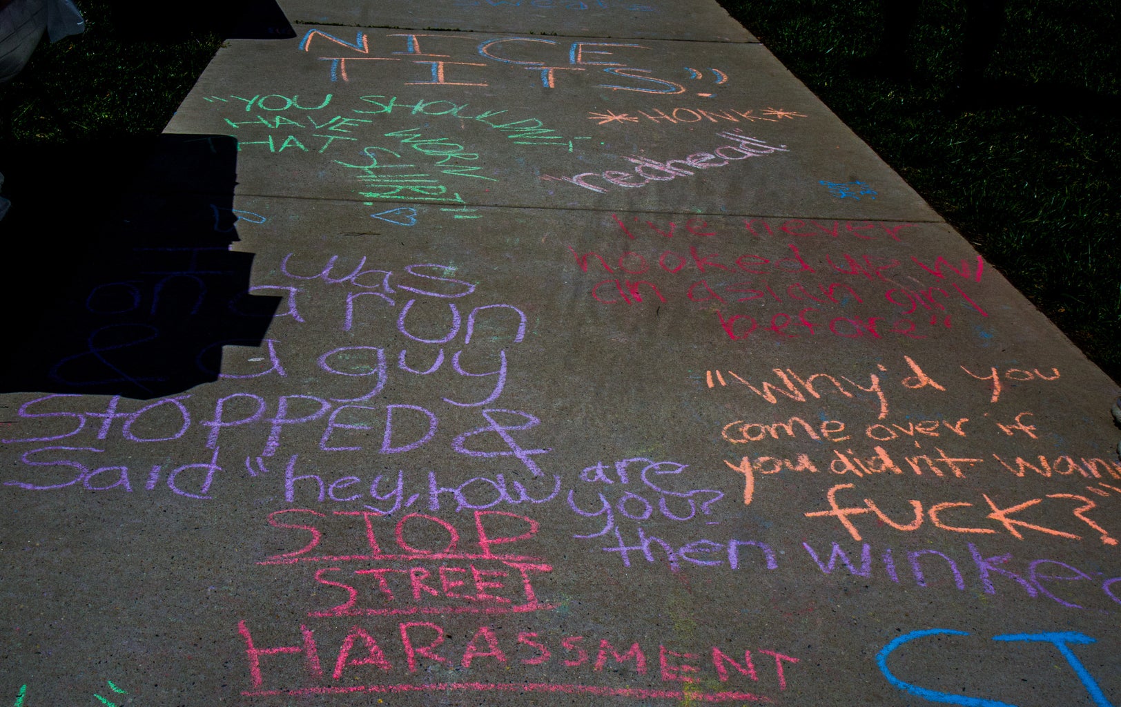 Chalk written on the sidewalk by students and community members discussing sexual harassment