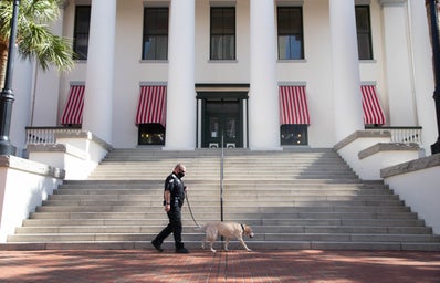 Law Enforcement Officer walking a k-9 in front of the Historic Old Florida Capitol building