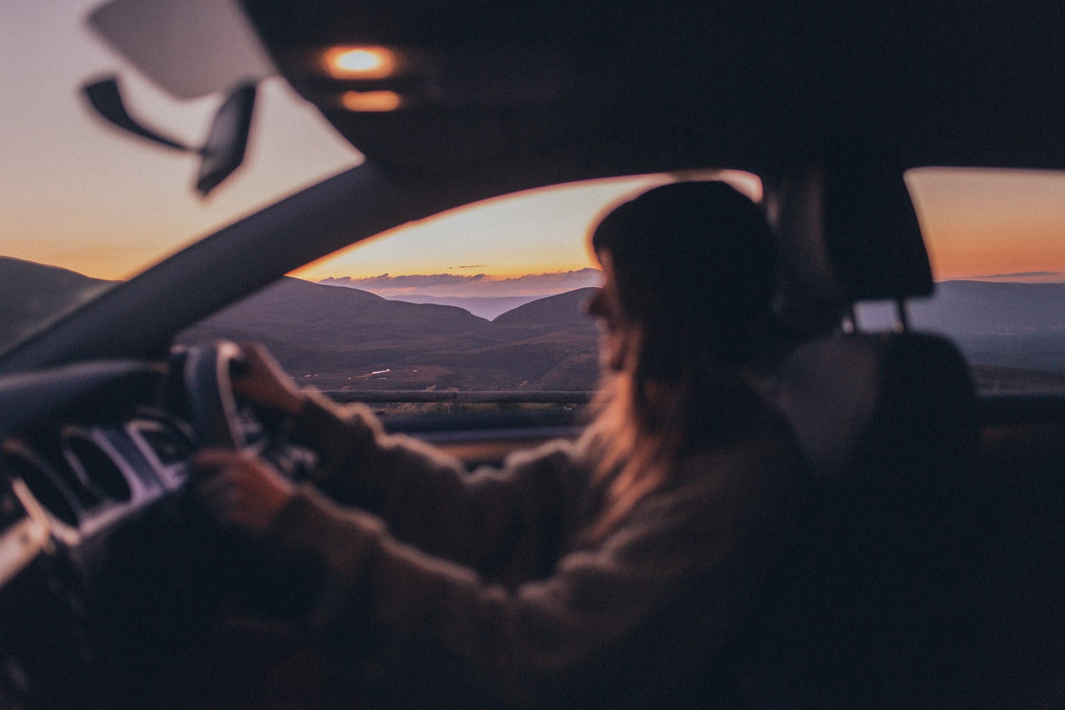 A blurry woman smiles while driving.