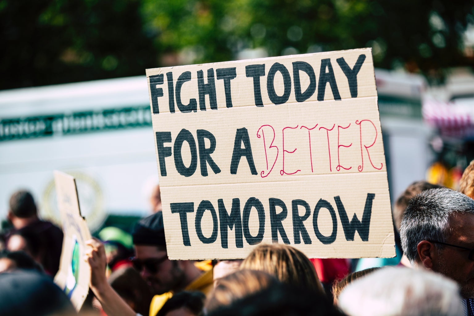 person holding a sign that says \"fight for a better tomorrow\"