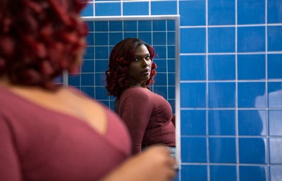 A young transgender woman looking at her reflection in a bathroom mirror?width=398&height=256&fit=crop&auto=webp
