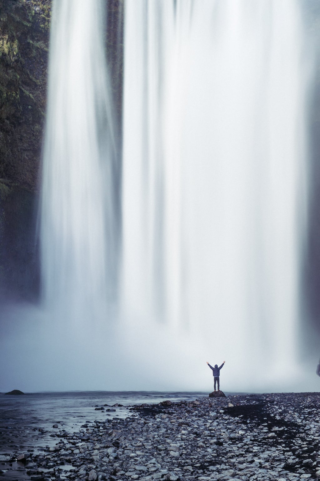 person standing beside waterfall