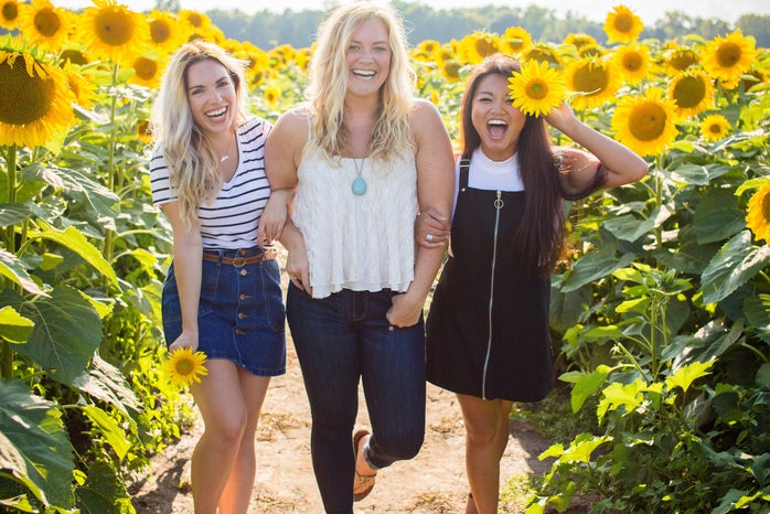 woman friends standing in a sunflower field