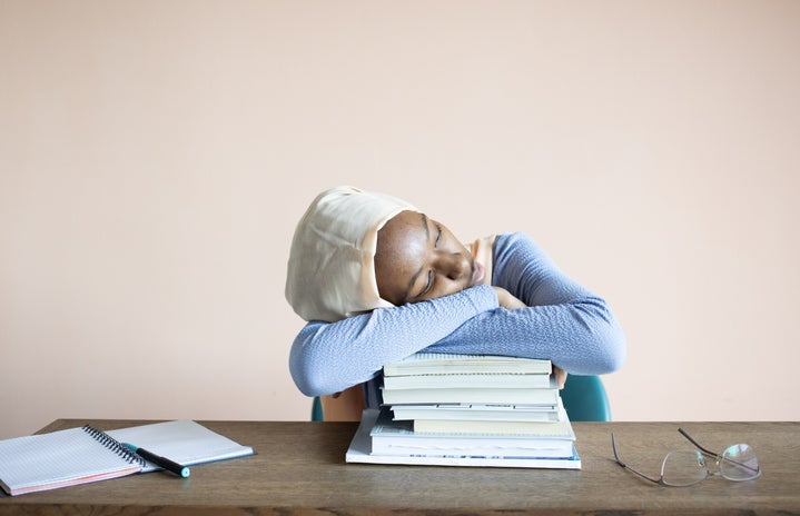 Student with head on books looking stressed