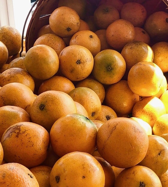 Many tangerines for sale, set up with an illusion that they\'re falling out of a basket.