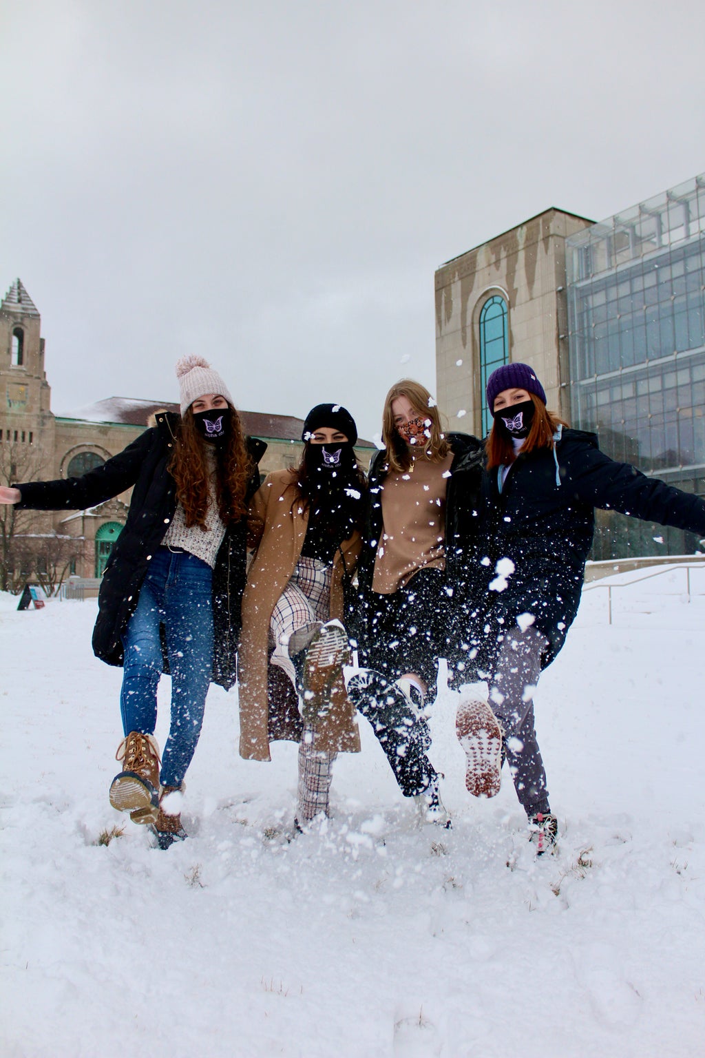 Four women kicking snow on campus