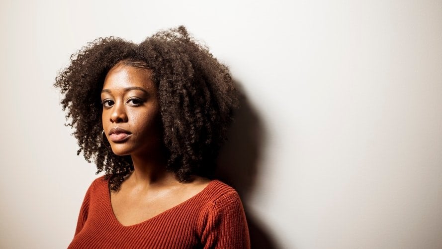 woman against a wall wearing a sweater