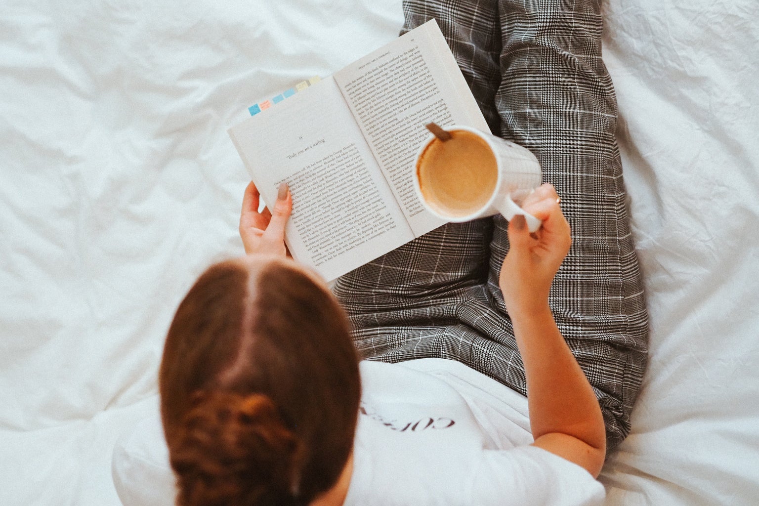 Woman Reading book in bed with coffee