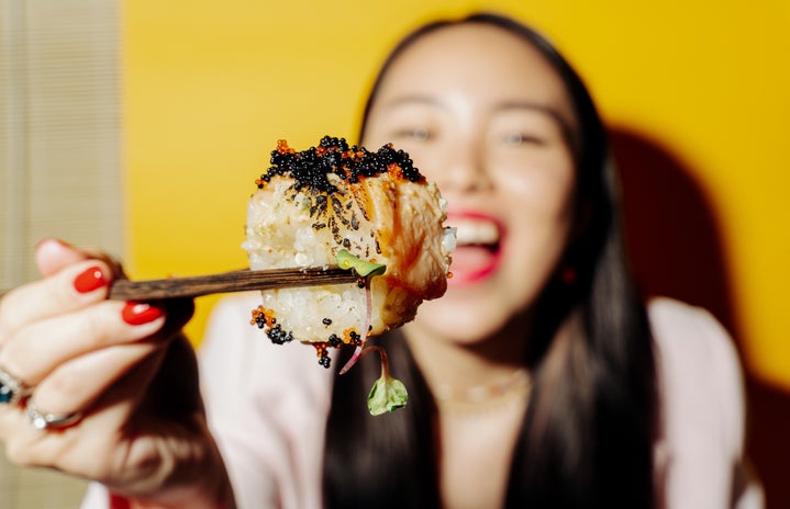 Woman holding sushi on chopstick
