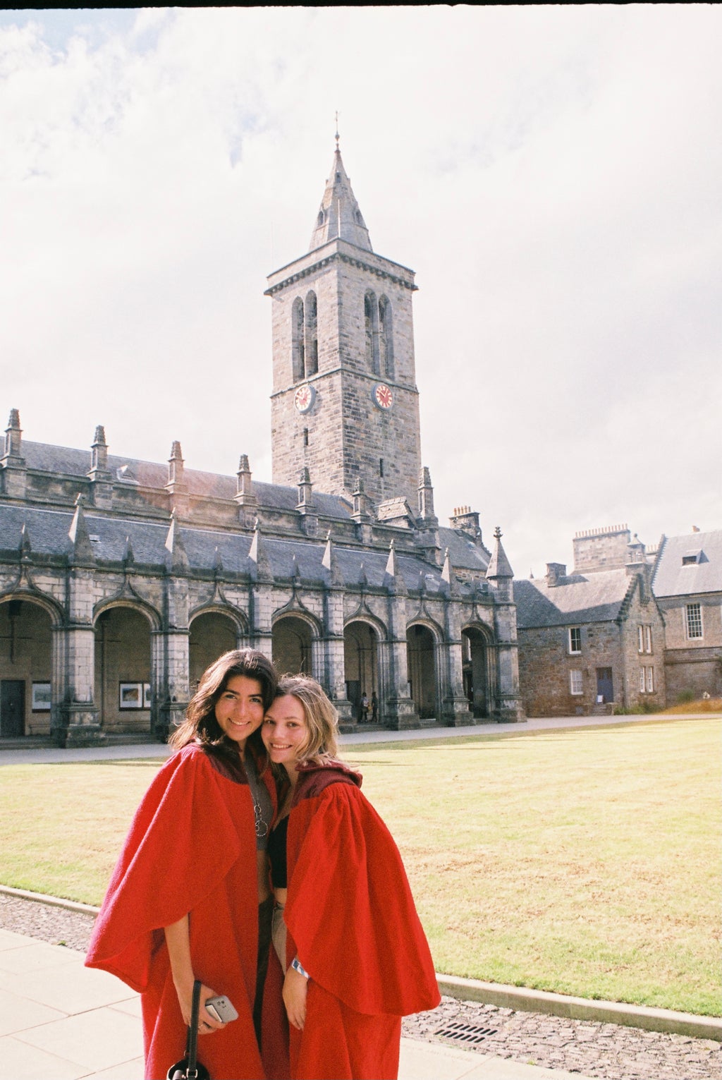 Girls in red cloaks outside a clock tower
