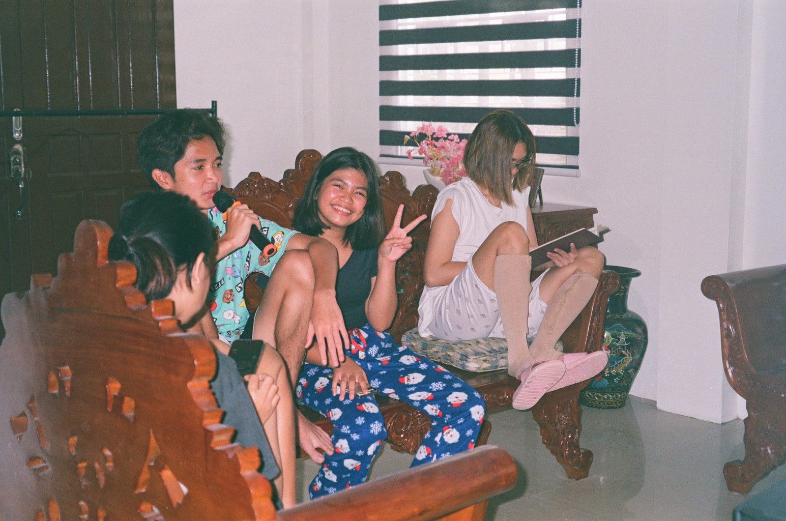 Film photo of people performing karaoke in the living room.