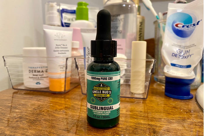 CBD oil on a dresser with other beauty products behind it