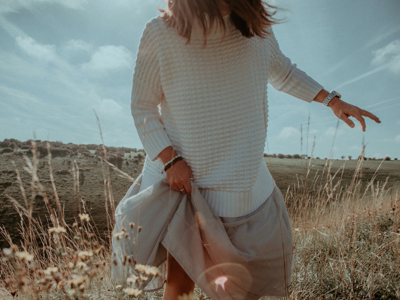 woman in white sweater and beige skirt in field