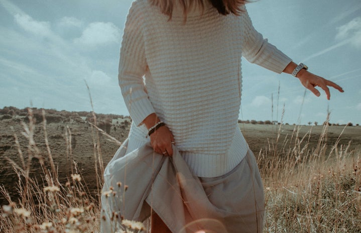 woman in white sweater and beige skirt in field