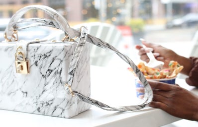 white purse with person eating dessert in the background