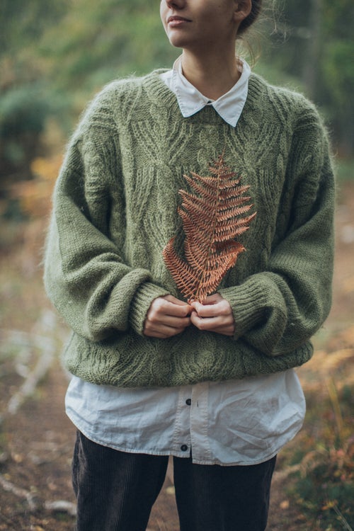 woman in sweater holding leaf