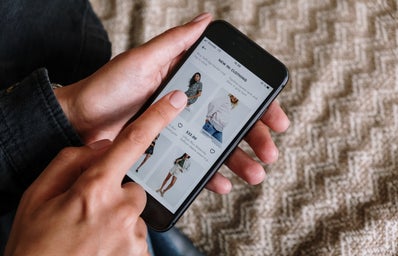 Person holding phone and shopping for clothes online