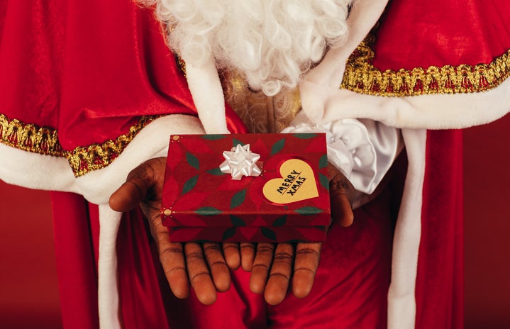 Santa Claus holding a present that reads \"Merry Christmas\"