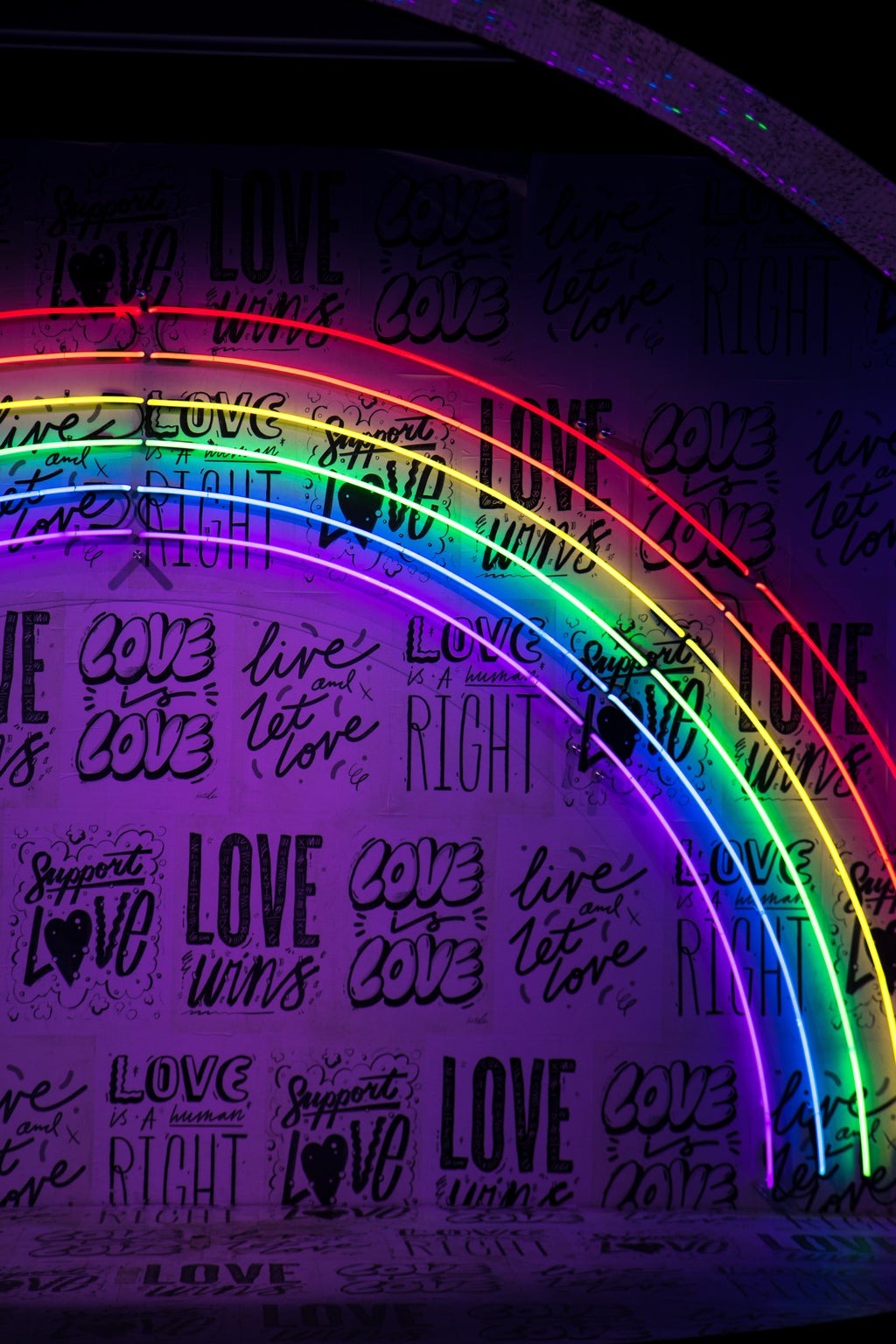 neon rainbow with background writing