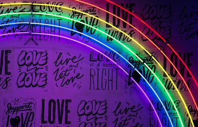 neon rainbow with background writing