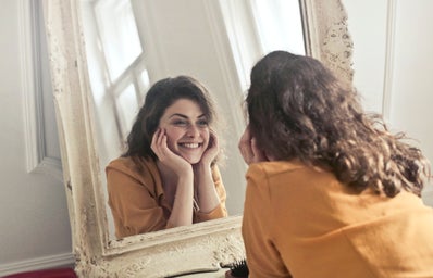 woman smiling at reflection in mirror