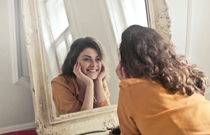 woman smiling at reflection in mirror by Andrea Piacquadio?width=719&height=464&fit=crop&auto=webp