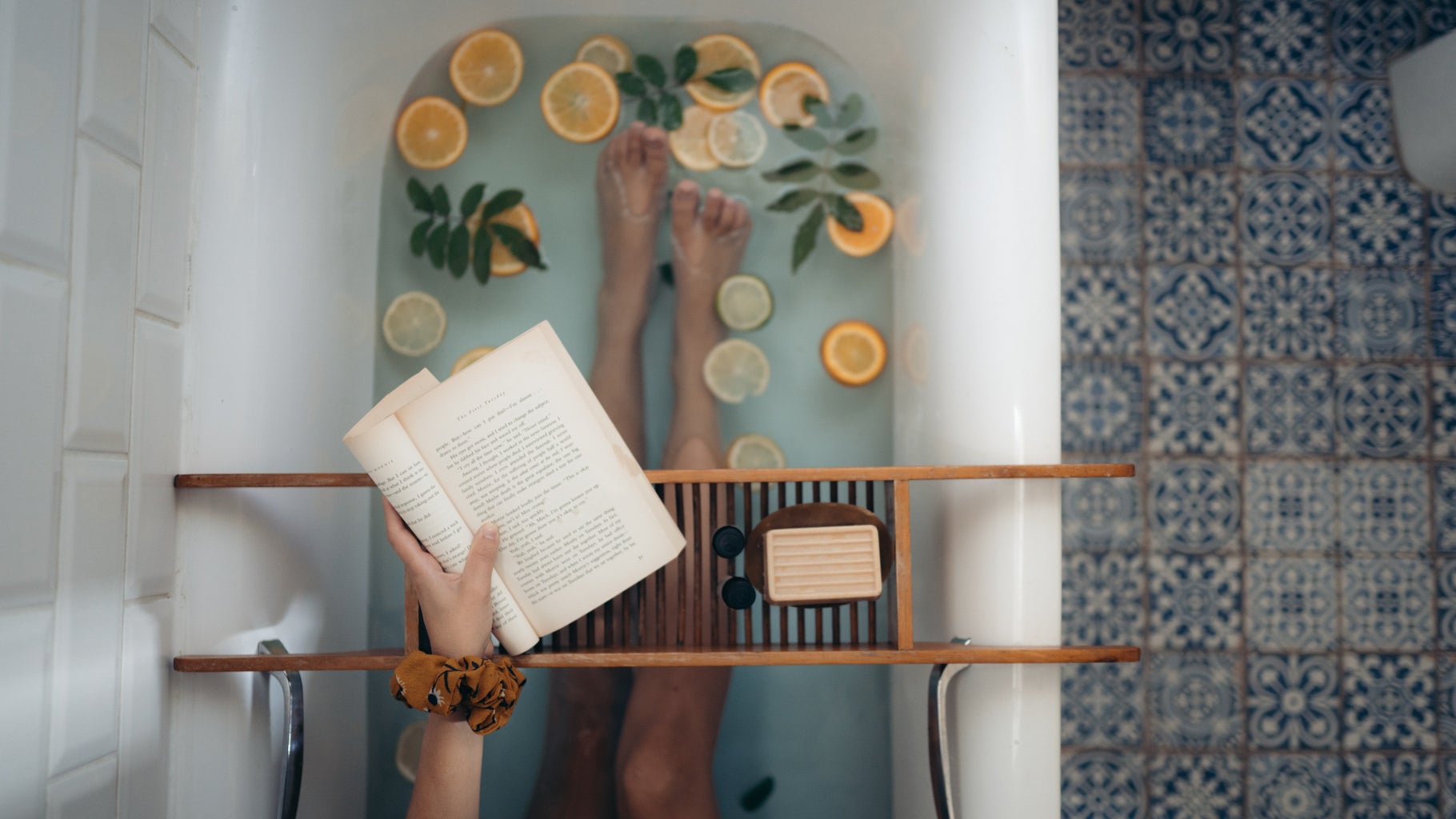 Person in a bathtub with lemons and herbs reading