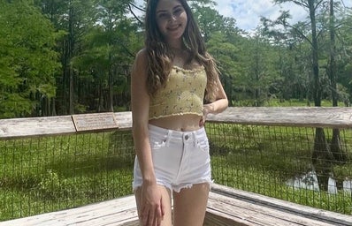 girl smiling and posing, yellow top white shorts