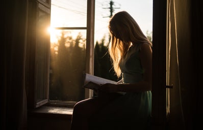 woman reading a book on a window seat