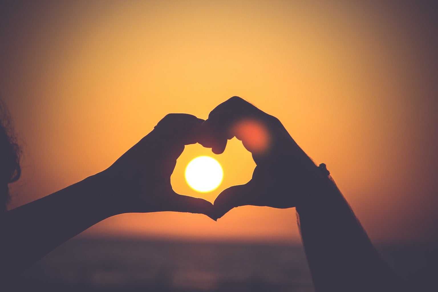 A couple making a heart at sunset